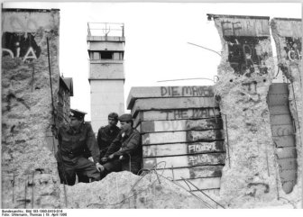 East German soldiers peering through a hole in the Berlin Wall. April 1990.